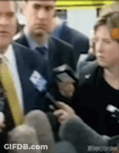 A Man In A Suit And Tie Is Talking To A Woman In A Black Dress . GIF
