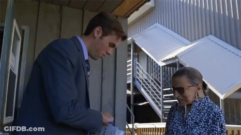A Man In A Suit And Tie Is Talking To A Woman In A Blue And White Dress GIF