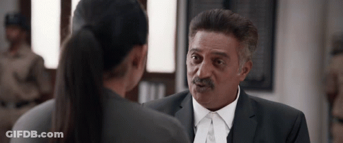 A Man In A Suit And Tie Is Talking To A Woman In A Ponytail GIF