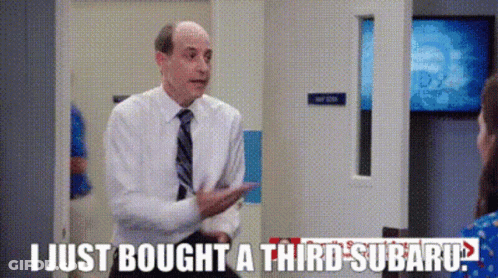A Man In A Suit And Tie Is Talking To A Woman In A Room . GIF