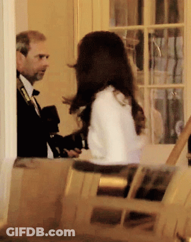 A Man In A Suit And Tie Is Talking To A Woman In A White Coat GIF