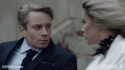 A Man In A Suit And Tie Is Talking To A Woman In A White Shirt . GIF
