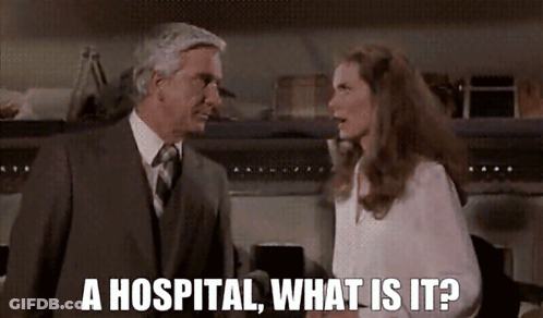 A Man In A Suit And Tie Is Talking To A Woman In A White Shirt Who Says " A Hospital What Is It ? " GIF