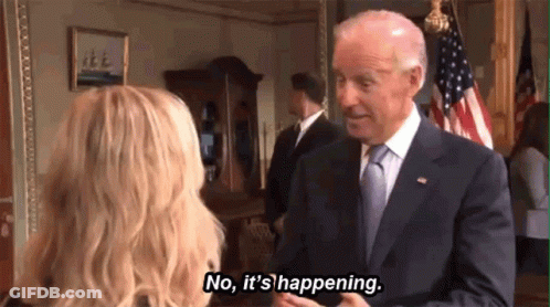 Man In Suit Talking To Woman In Front Of Flag GIF