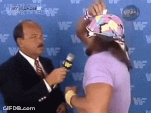 A Man In A Suit And Tie Is Talking To A Wrestler In A Purple Shirt While Holding A Microphone . GIF