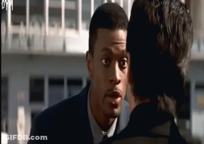 A Man In A Suit And Tie Is Talking To Another Man In A Black Suit GIF