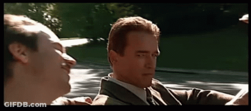 A Man In A Suit And Tie Is Talking To Another Man In A Convertible GIF