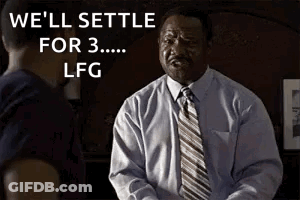 A Man In A Suit And Tie Is Talking To Another Man In A Dark Room . GIF