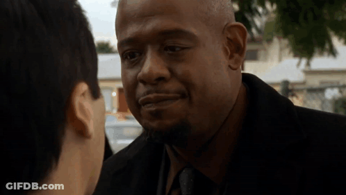 A Man In A Suit And Tie Is Talking To Another Man In A Park . GIF