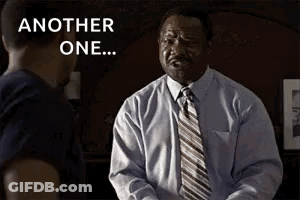 A Man In A Suit And Tie Is Talking To Another Man In A Room . GIF