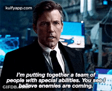A Man In A Suit And Tie Is Talking To Another Man In A Room . GIF