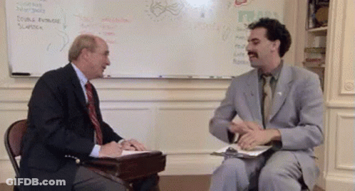 A Man In A Suit And Tie Is Talking To Another Man In Front Of A White Board GIF