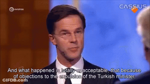 A Man In A Suit And Tie Is Talking To Another Man On A Tv Show GIF