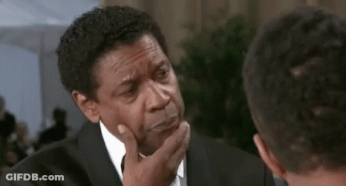 A Man In A Suit And Tie Is Talking To Another Man While Touching His Face . GIF