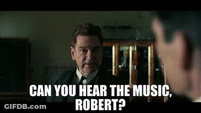 A Man In A Suit And Tie Is Talking To Another Man With The Words Can You Hear The Music Robert GIF