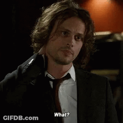 A Man In A Suit And Tie Is Talking To Someone While Holding His Neck . GIF