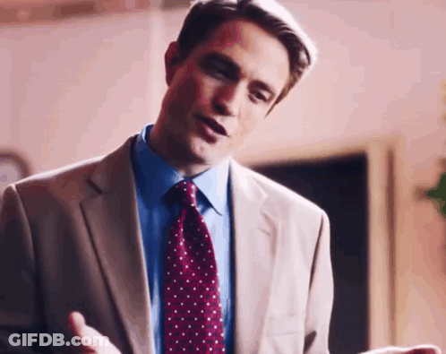 A Man In A Suit And Tie Is Talking To Someone While Standing In A Room . GIF