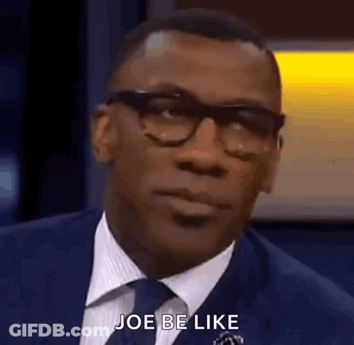 A Man In A Suit And Tie Is Talking To Someone While Wearing Glasses . GIF