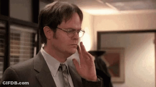 A Man In A Suit And Tie Is Touching His Face With His Finger . GIF
