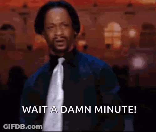 A Man In A Suit And Tie Is Waiting For A Damn Minute . GIF