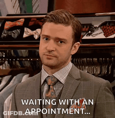 A Man In A Suit And Tie Is Waiting With An Appointment In A Store . GIF