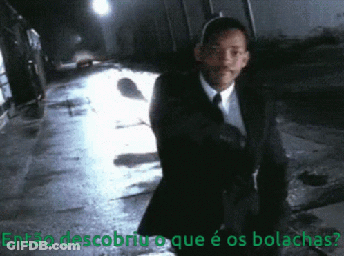 A Man In A Suit And Tie Is Walking Down A Dark Street With The Words Então Descobriu O Que É Os Bolachas GIF