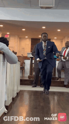 A Man In A Suit And Tie Is Walking Down A Hallway With A Gif Maker App Open GIF