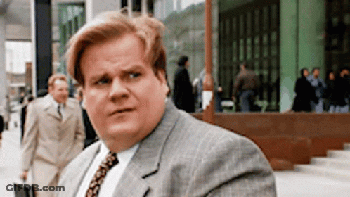 A Man In A Suit And Tie Is Walking Down A Sidewalk . GIF