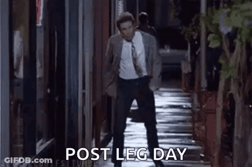 A Man In A Suit And Tie Is Walking Down A Sidewalk At Night And Talking On A Cell Phone . GIF