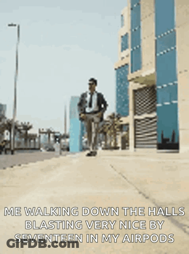 A Man In A Suit And Tie Is Walking Down A Sidewalk With His Hands In His Pockets GIF