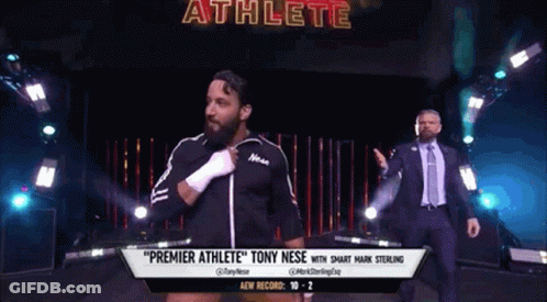 A Man In A Suit And Tie Is Walking Down A Wrestling Ring With A Man In A Suit Behind Him . GIF