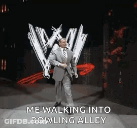 A Man In A Suit And Tie Is Walking Into A Bowling Alley On A Stage . GIF