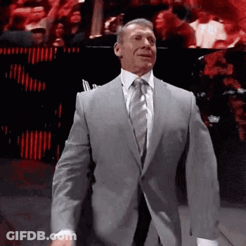A Man In A Suit And Tie Is Walking On A Stage . GIF