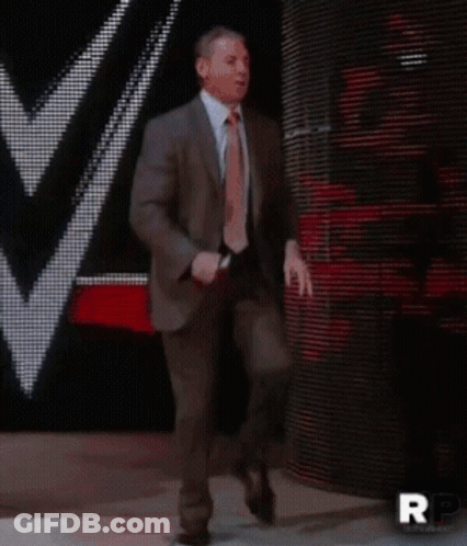 A Man In A Suit And Tie Is Walking On A Stage With Rp Written On The Bottom Right GIF