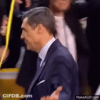 A Man In A Suit And Tie Is Walking Through A Crowd . GIF