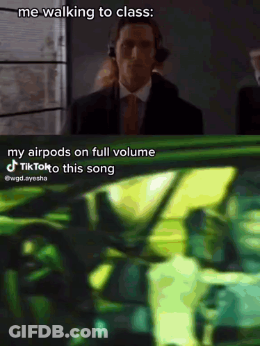 A Man In A Suit And Tie Is Walking To Class While Wearing Headphones GIF