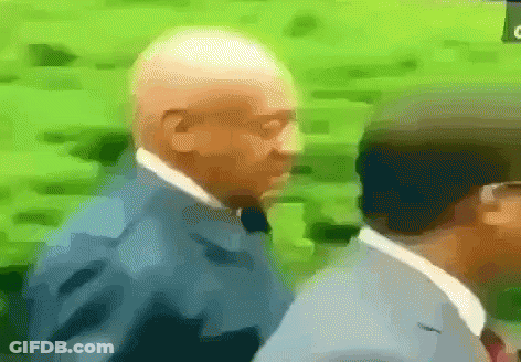 A Man In A Suit And Tie Is Walking With Another Man GIF
