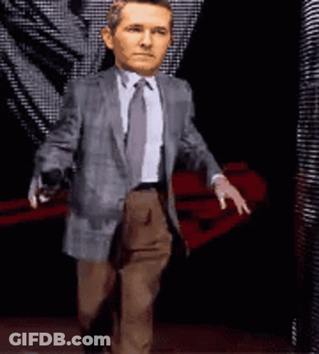 A Man In A Suit And Tie Is Walking With His Hands Outstretched GIF