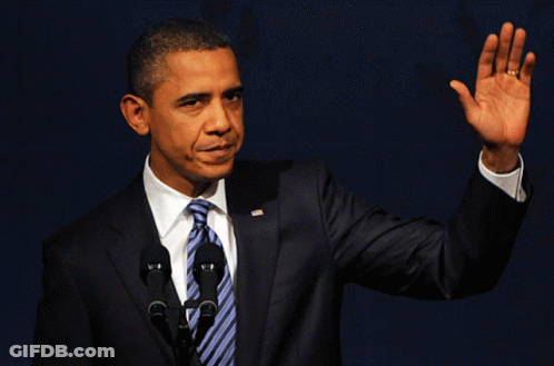 A Man In A Suit And Tie Is Waving At The Camera GIF