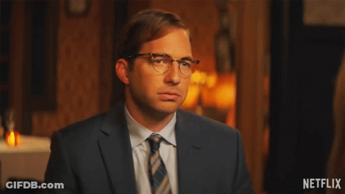 A Man In A Suit And Tie Is Waving His Hands With A Netflix Logo In The Corner GIF