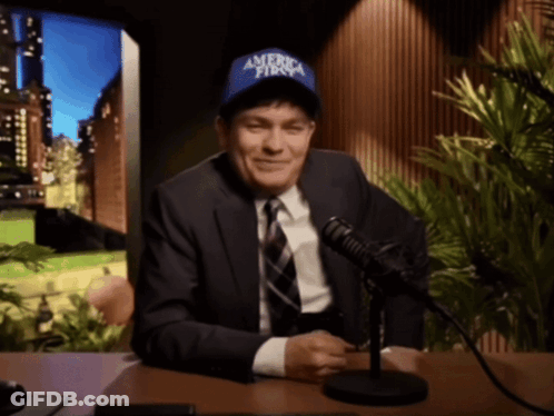 A Man In A Suit And Tie Is Wearing A Blue Hat That Says America First GIF