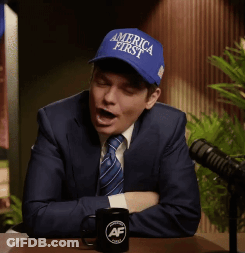 A Man In A Suit And Tie Is Wearing A Blue Hat That Says America First GIF
