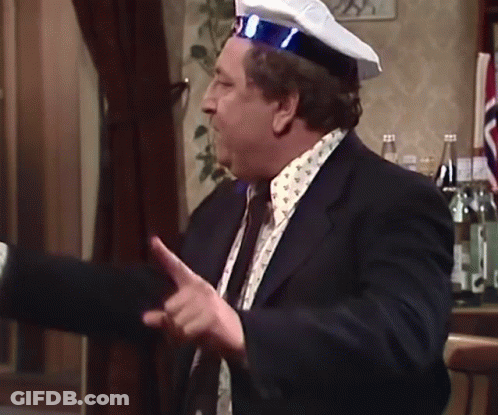 A Man In A Suit And Tie Is Wearing A Captain 'S Hat GIF