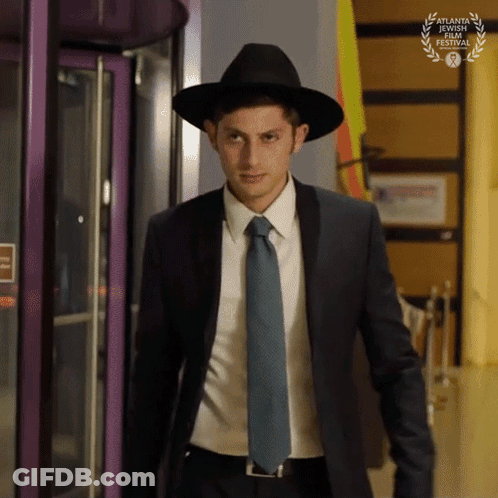 A Man In A Suit And Tie Is Wearing A Hat And A Laurel Wreath From The Atlanta Jewish Film Festival GIF