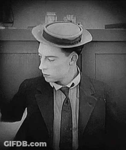 A Man In A Suit And Tie Is Wearing A Hat And A Tie . GIF