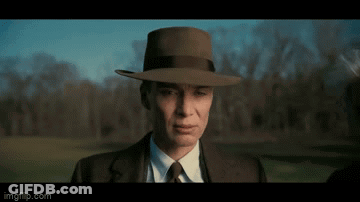 A Man In A Suit And Tie Is Wearing A Hat . GIF