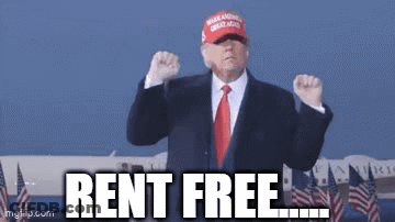 A Man In A Suit And Tie Is Wearing A Hat That Says Rent Free .. GIF