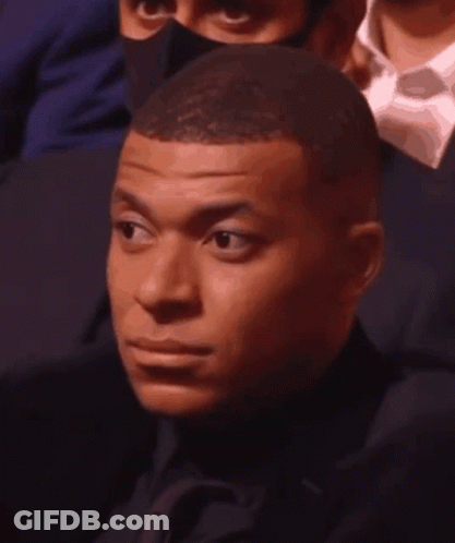 A Man In A Suit And Tie Is Wearing A Mask And Making A Funny Face . GIF