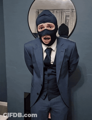 A Man In A Suit And Tie Is Wearing A Mask GIF