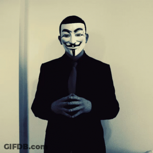 A Man In A Suit And Tie Is Wearing A Mask GIF
